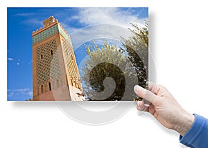 Hand holding a postcard about the most important mosque in Marrakech, called Kutubiyya or Koutoubia