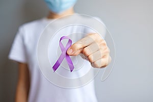 Hand holding purple Ribbon for Pancreatic, Esophageal, Testicular cancer, world Alzheimer, epilepsy, lupus, Sarcoidosis,