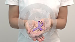 Hand holding purple Ribbon for Pancreatic, Esophageal, Testicular cancer, world Alzheimer, epilepsy, lupus, Sarcoidosis,