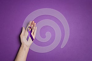Hand holding Purple ribbons on a p urple background. World epilepsy day