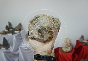 A hand is holding a raw of fluorite rock stone.