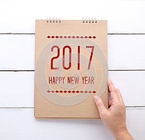 Hand holding recycle paper notebook with Happy new year 2017 on