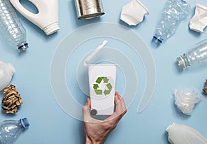 Hand holding a recycling garbage bin with lots of waste packaging