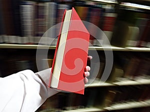 Hand Holding Red Book in Library