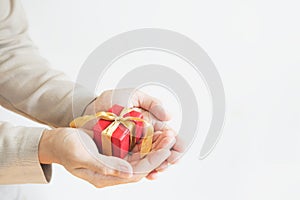 Hand holding red gift box, on white background with copy space