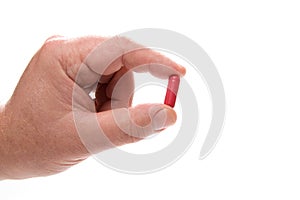 Hand holding red medical pill