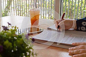 hand holding red pen over blurred paperwork for proofreading