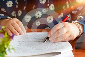 hand holding red pen over blurred paperwork for proofreading