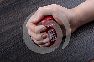 Hand holding a red phone booth