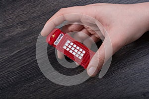 Hand holding a red phone booth