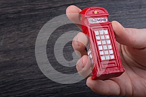 Hand holding a red phone booth