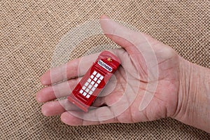 Hand holding a red phone booth