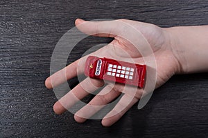 Hand holding a red phone booth