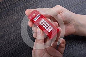 Hand holding a red phone booth