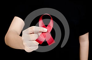 Hand holding red ribbon on black background sign of world aids d