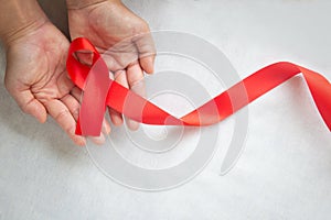 Hand holding Red ribbon on white background with copy space, the solidarity of people living with HIV, AIDS symbol, and for the