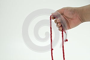 Hand holding red tasbih or rosary beads over white background.
