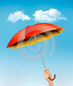 Hand holding a red and yellow umbrella against a blue sky