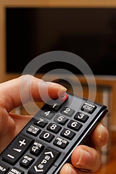 Hand holding remote control for television, choosing channel in TV