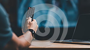 hand holding remote to press button to turn on or off television at home concept. person using remote control tv to select and