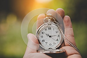 Hand holding retro stopwatch in natural background.