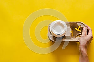 Hand holding reuse paper tray with a recycle cup of coffee on yellow paper background
