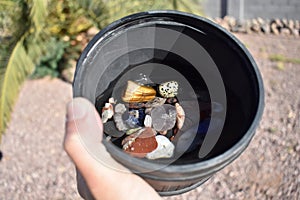 Hand Holding Rock Tumbler Barrel Full of Assorted Polished Stones