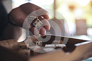Hand holding and rolling wooden dices
