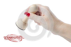Hand holding a rubber stamp with the word compliance photo