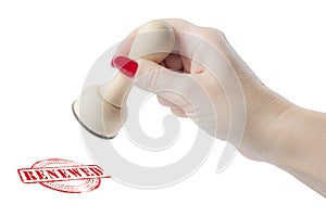 Hand holding a rubber stamp with the word renewed photo