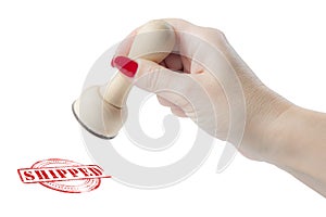Hand holding a rubber stamp with the word shipped