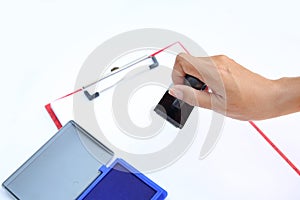 Hand holding rubber stamper with blue Ink padbox on white paper