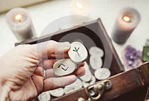 Hand holding rune stones, taking out of the wooden box container, self-prophecy concept.