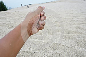 Hand holding a sand over desert sand
