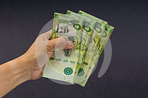 Hand holding saudi riyal bank notes on black background.