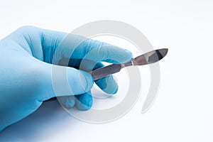 Hand holding scalpel. Palm of surgeon dressed in blue glove holding scalpel. Concept photo for surgeries, procedures, treatment, p