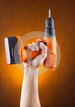 hand holding a screwdriver on an orange background.