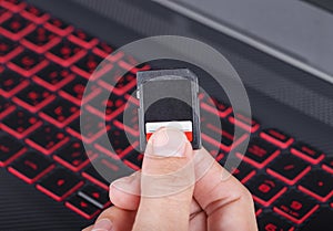 Hand holding SD card with laptop