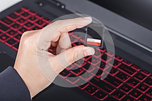 Hand holding SD card with laptop