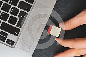 hand holding SD Flash card drive and insert it in the laptops