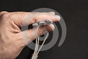 Hand is holding set of smartphone connectors: lightning, micro-usb and type-c cables