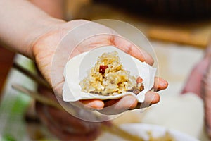 Hand Holding Shaomai Wrapper with Sticky Rice & Pork Filling