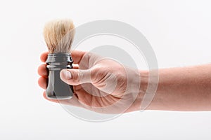 Hand holding a shaving brush on white background