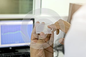 Hand holding sheet PMMA acrylic plate to apply UV sunscreen for the measurement of radiation protection of cosmetic by using photo