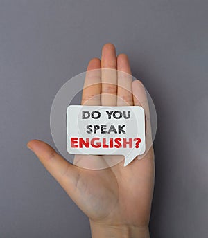 A hand holding a sign that says Do you speak English