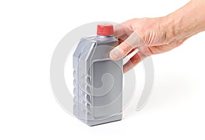 Hand holding silvery measuring bottle with red lid. Brake fluid