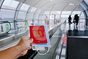 Hand holding Singapore passport walking on travelator, travolator moving walkway