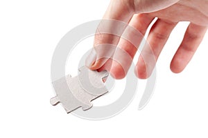 Hand holding a single blank empty jigsaw puzzle piece, laying, putting down from above gesture isolated on white, cut out. Fingers