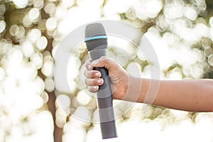 hand holding a single microphone against colourful background,singing contest.