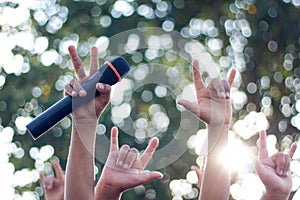 hand holding a single microphone against colourful background,singing contest.